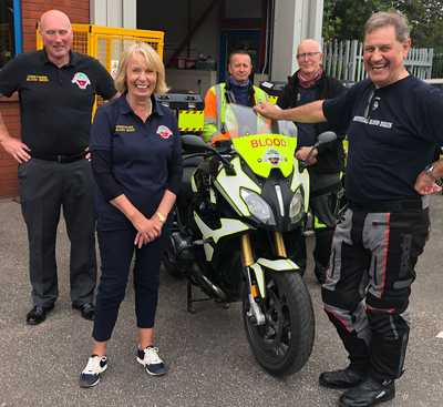 Group of Derbyshire Blood Bike volunteers of mixed gender standing around a Blood Bike